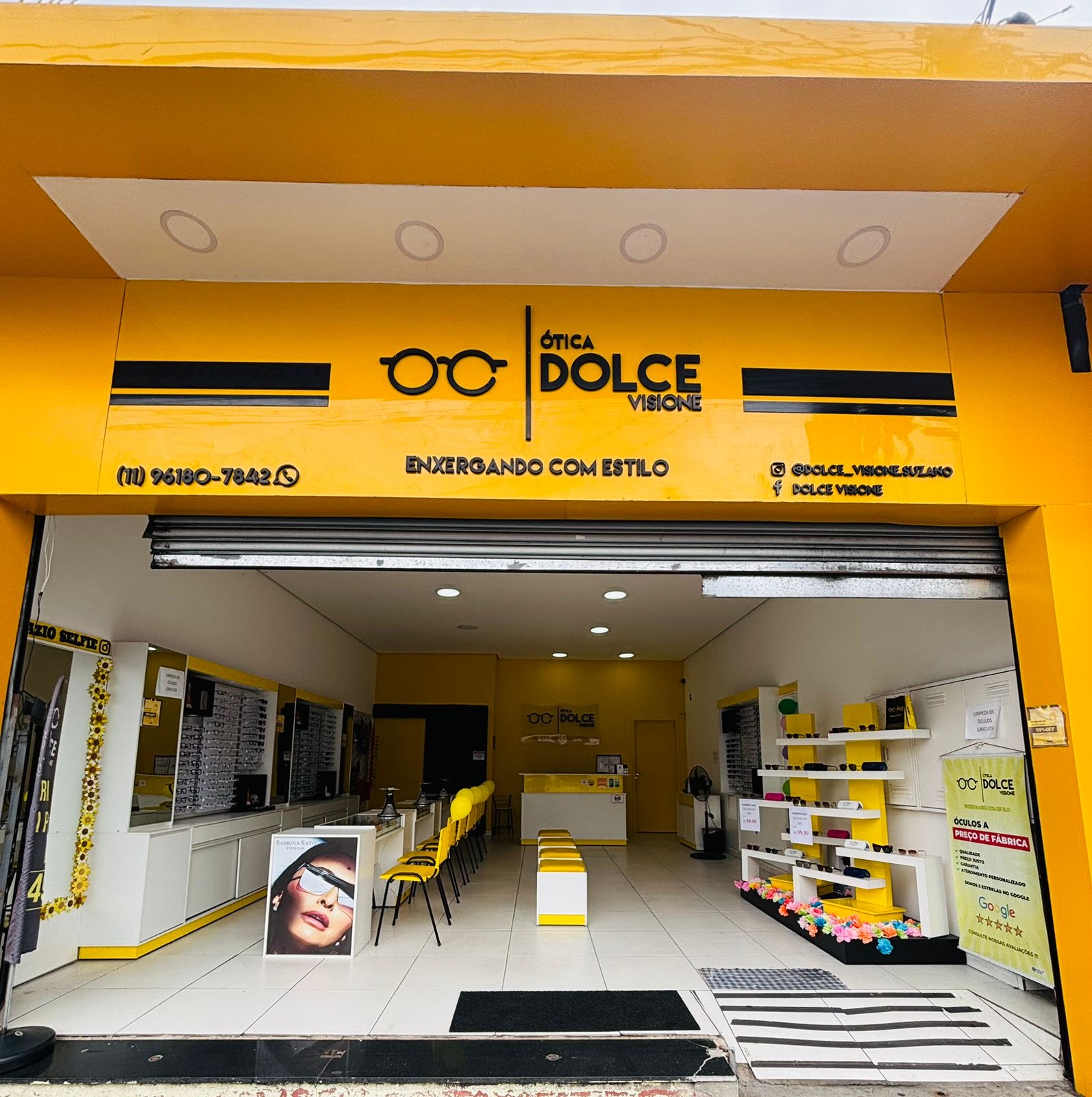 Fachada amarela da Ótica Dolce Visione, com entrada aberta e expositores de óculos no interior
